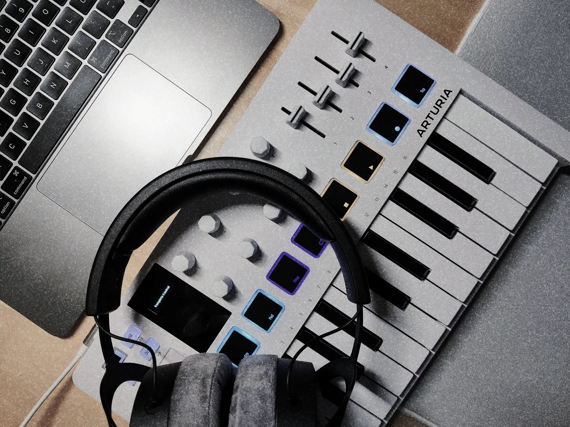 Compact MIDI keyboard, headphones, and a laptop
